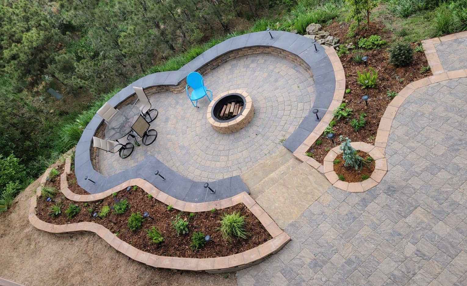 Curved stone patio with fire pit and planted terraces