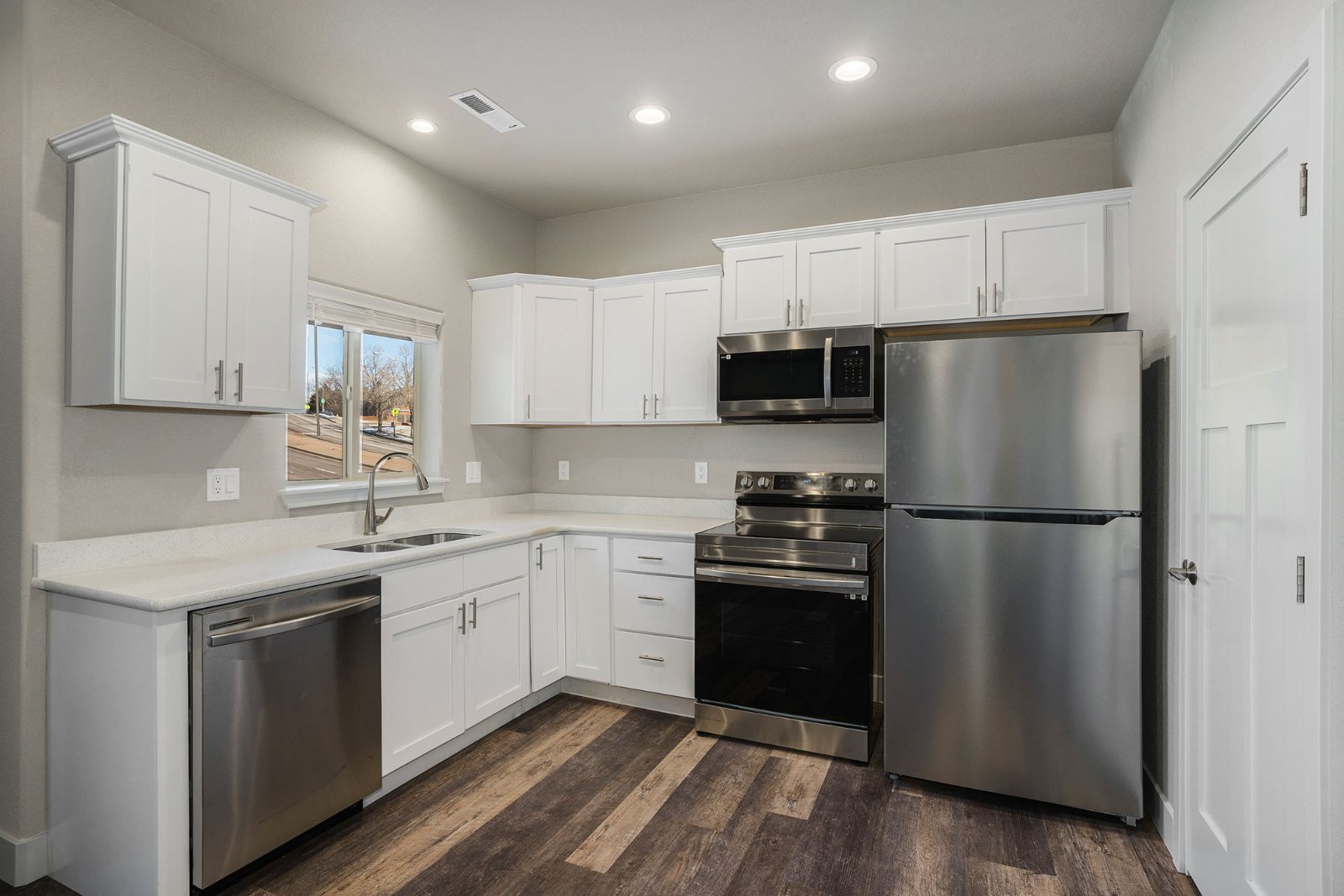 Unit kitchen with white shaker cabinets and stainless appliances