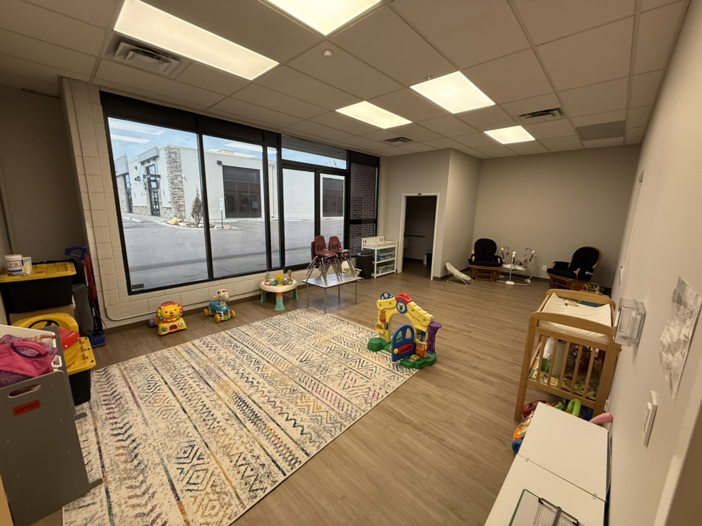 Nursery with a large window, play area, rug and gliders