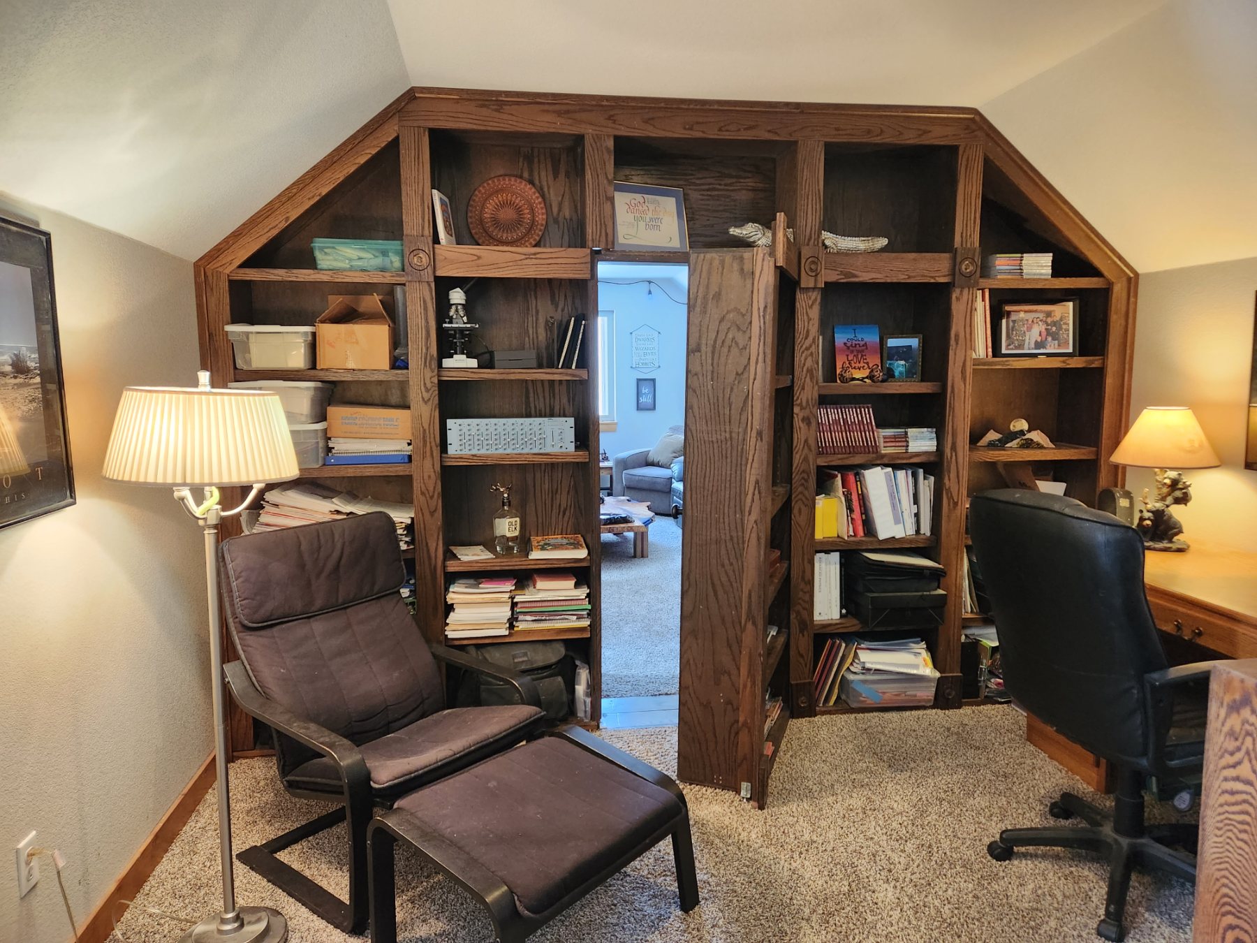 Built-in oak bookcase wall with a hidden door swung open